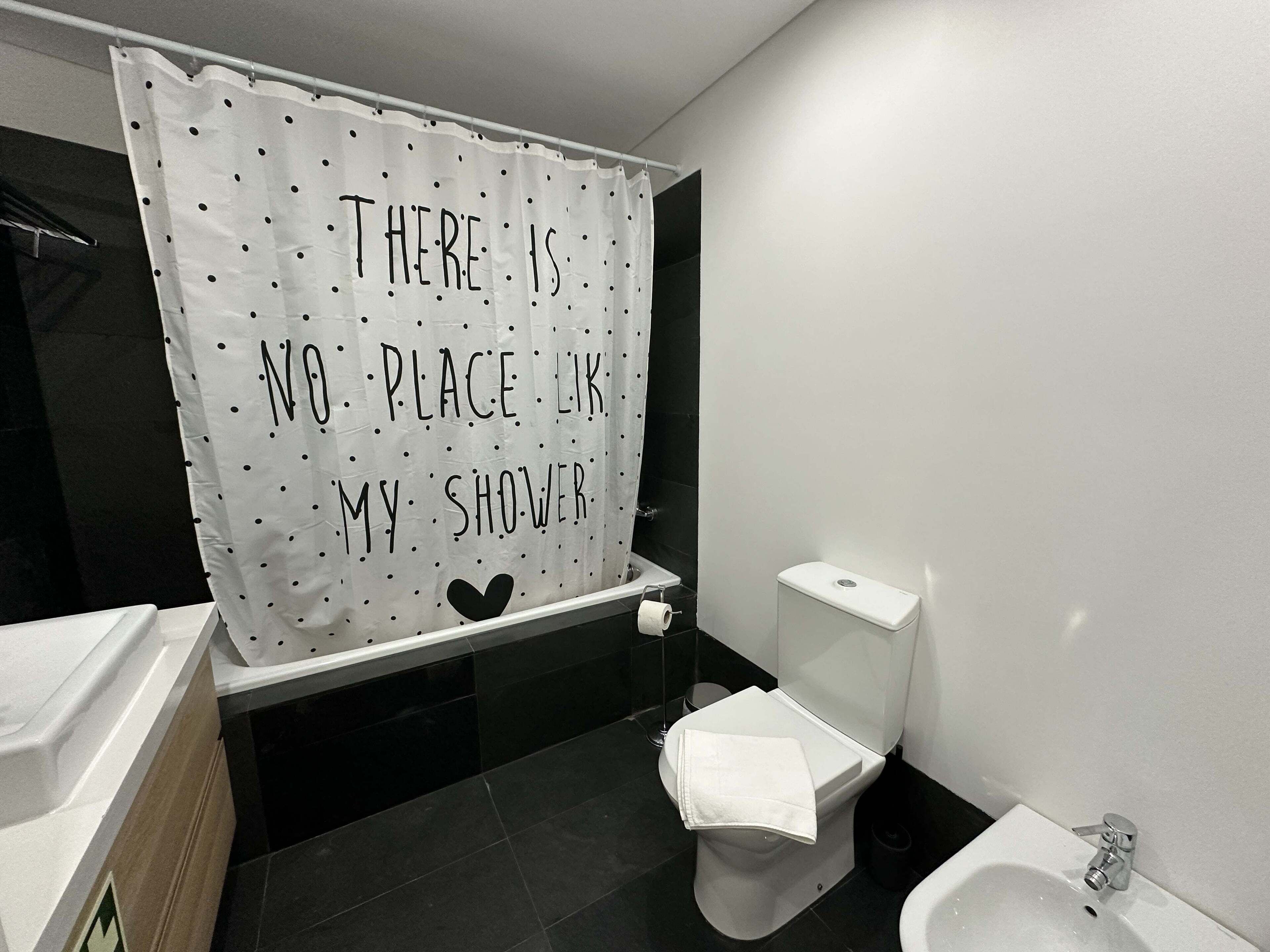 Un baño con cortina de ducha que dice: 'No hay lugar como mi ducha'.