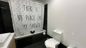 Un baño con cortina de ducha que dice: 'No hay lugar como mi ducha'.
