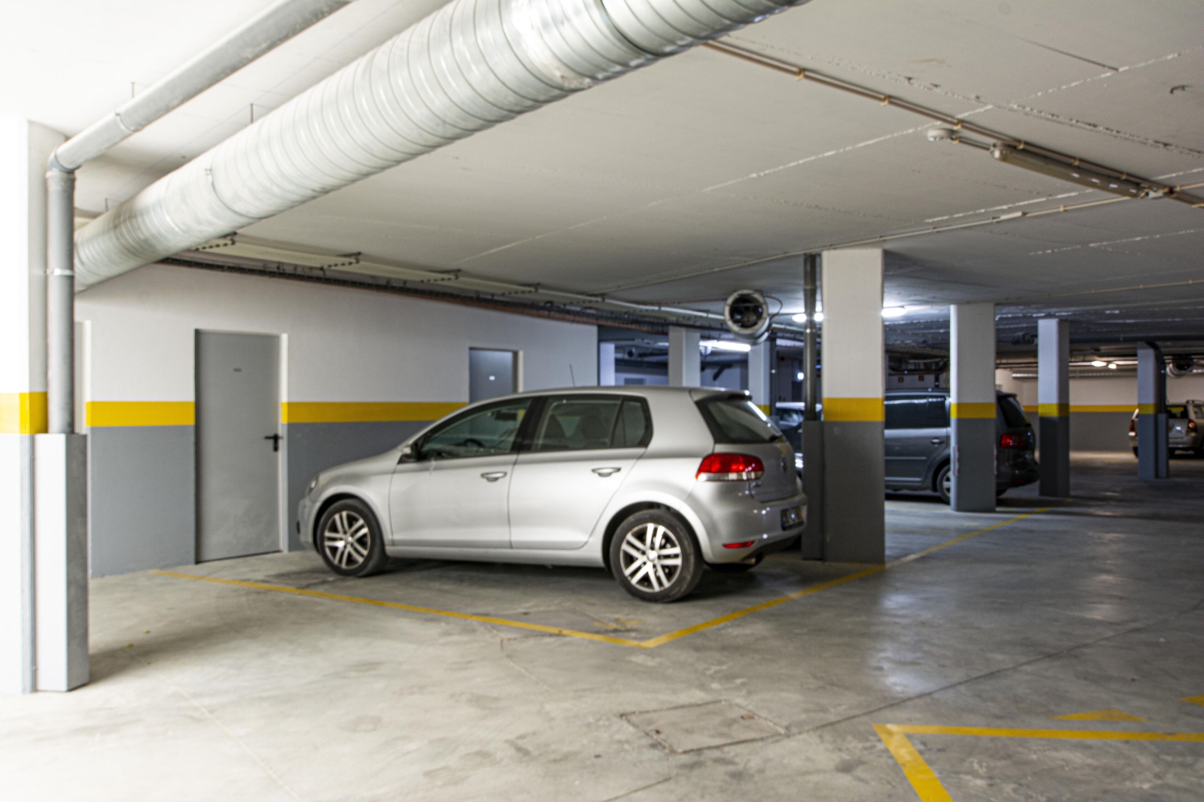 Un garaje para coches con un automóvil plateado estacionado en un espacio reservado.