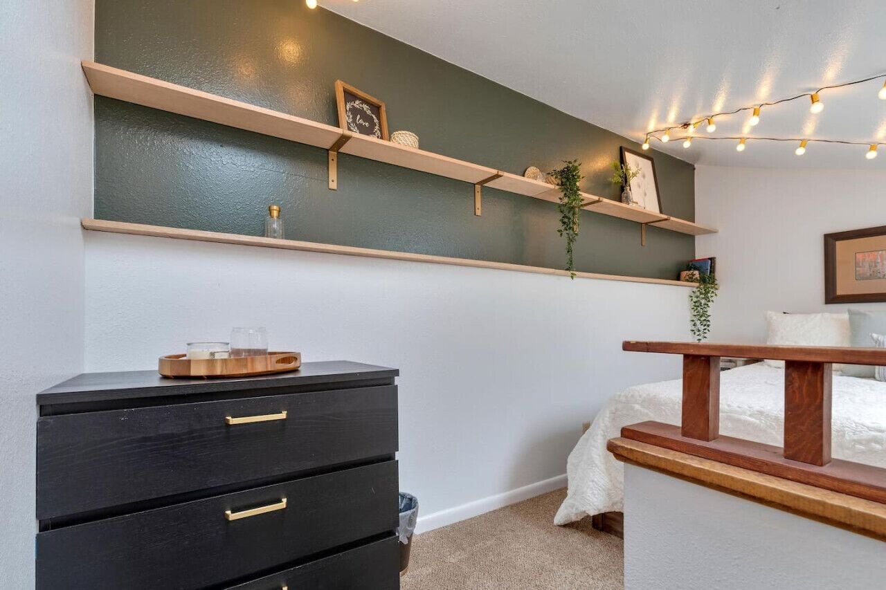 Une chambre à coucher comprenant un lit, une commode et deux étagères ornées d’objets décoratifs.