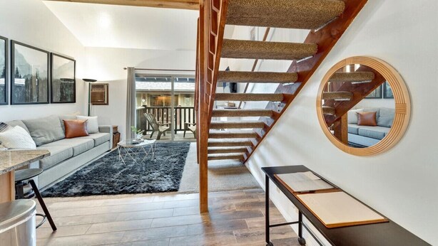 Een moderne woonkamer met een trap, een ronde spiegel en een bank.