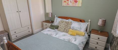 A bedroom with a bed, nightstands, a wardrobe, and a painting on the wall.