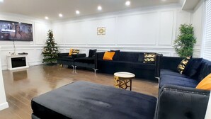 A modern living room with a black sectional sofa, a small round table, and a Christmas tree.