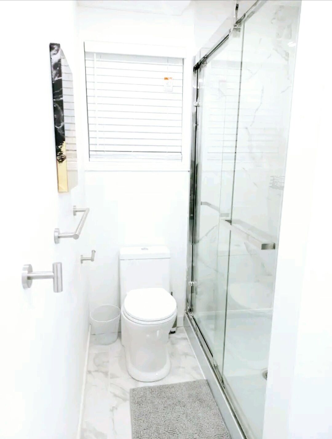 Une petite salle de bain comprenant des toilettes, une petite poubelle et une cabine de douche en verre.