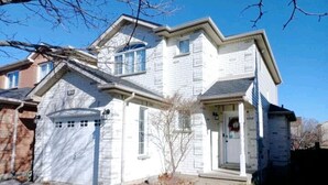 A two-story house with a garage, a small front porch, and a brick pathway leading to the entrance.