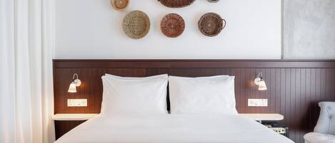 A hotel room with a bed, two bedside tables, a chair, and wall-mounted baskets.