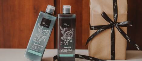 Two bottles of Ruby Care Mad Muse products, a gift bag, and a ribbon.