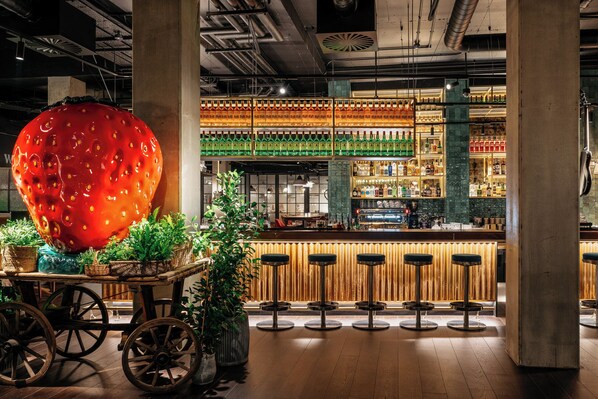 A bar area with a large red spherical decoration, wooden stools, and a variety of bottles on shelves. - Ruby Molly Hotel Dublin by IHG (Dublin)