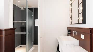 Ein modernes Badezimmer mit Dusche, Waschtisch mit Spiegel und weißem Waschbecken.