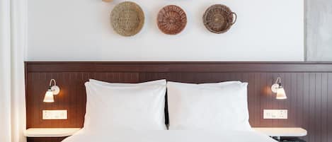 A bed with white linens, a wooden headboard, two bedside lamps, and a wall with woven baskets.