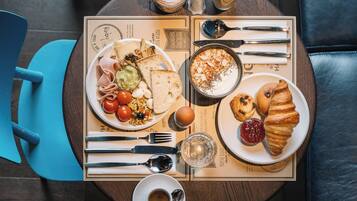 Una escena de desayuno con diversos alimentos, utensilios y una taza de café sobre una mesa.