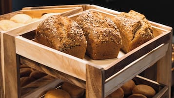 A wooden bread display with various types of bread, including seeded and round loaves.