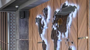 A modern interior with a wooden wall, a cushioned bench, and a decorative light fixture. - Shymkent Park Hotel (Shymkent)