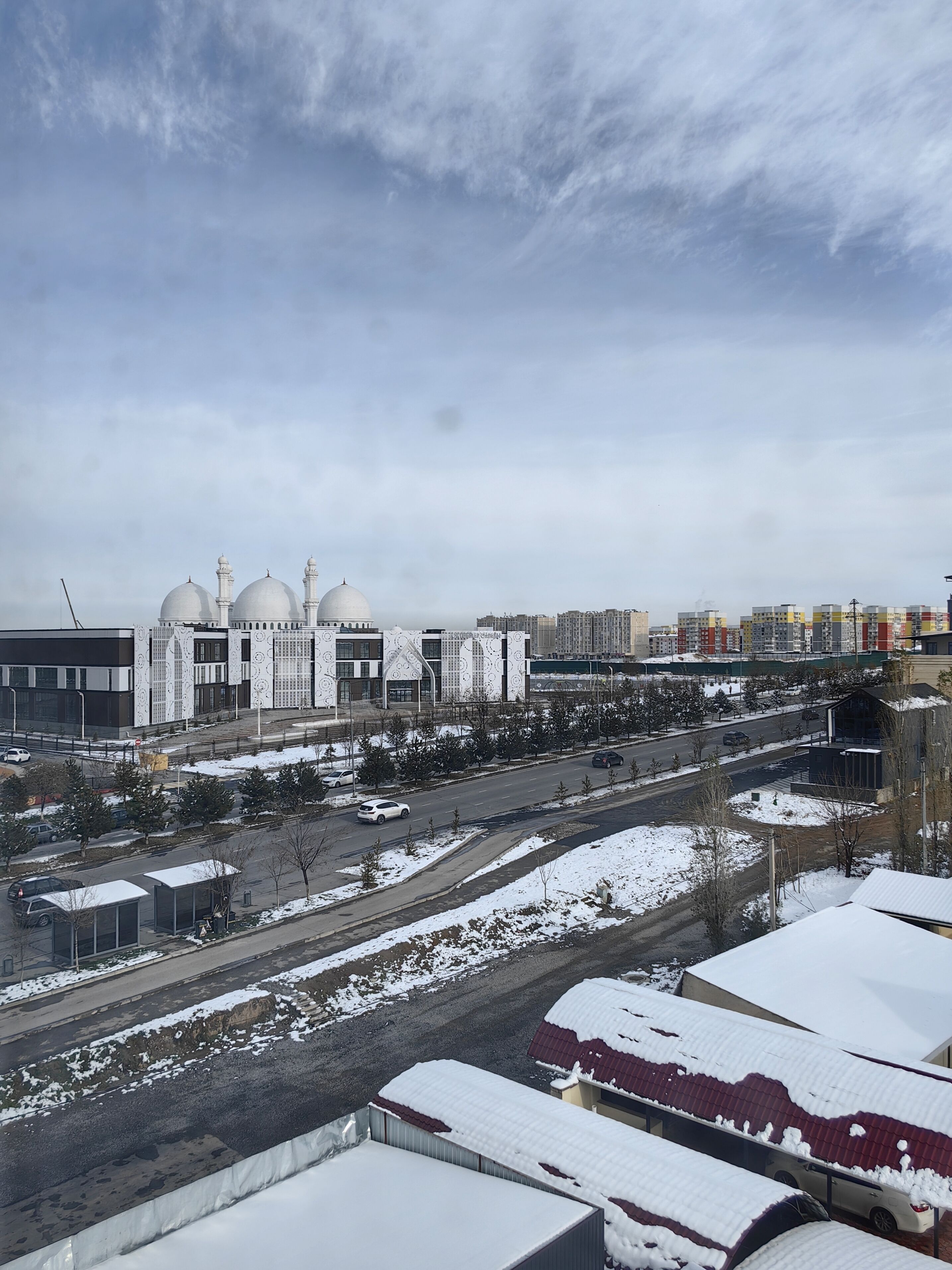 Un grand bâtiment doté de plusieurs dômes, entouré d’un paysage enneigé et de voitures garées.