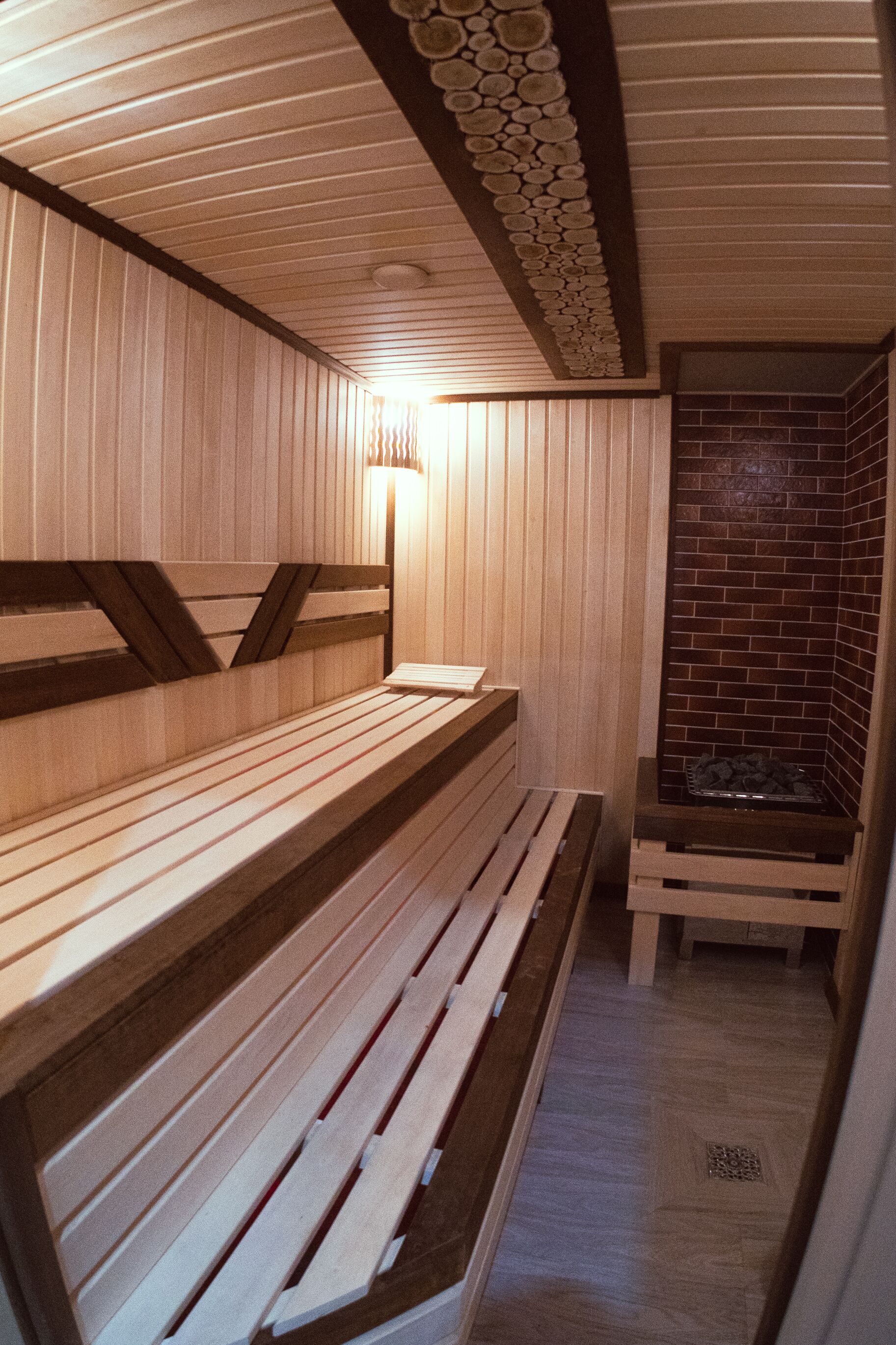 A sauna with wooden benches and a brick wall.