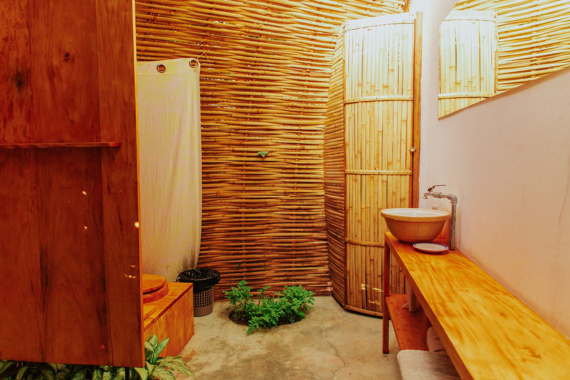 Un baño pequeño con un banco de madera, un lavamanos y una ducha.
