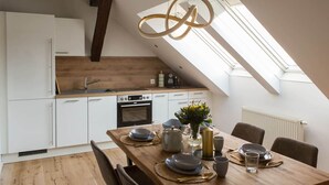 A modern kitchen with white cabinets, a wooden countertop, and a skylight above the dining area. - Modernes Apartment im Zentrum der Stadt (Graz)