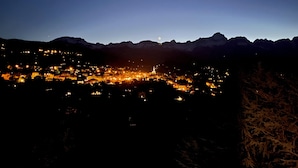 Ein Nachtblick auf eine Stadt mit beleuchteten Gebäuden und Bergen im Hintergrund.