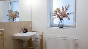 A bathroom with a white sink, a mirror, a window with a view, and a radiator.
