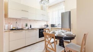 Una cocina moderna con armarios blancos, encimera negra y una zona de comedor con una mesa redonda y sillas de madera.