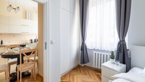 Un dormitorio moderno con cama, mesita de noche y ventana con cortinas.