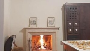 A room with a fireplace, a dining table, and a cabinet. - Locanda di Posta (L'Aquila)