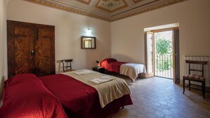 A room with two beds, a wooden wardrobe, a small table, and a bench. - Locanda di Posta (L'Aquila)