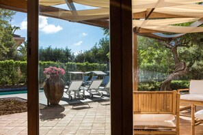 A patio with a pool, lounge chairs, a large vase with flowers, and a wooden table. - Villa Mazzaforno a Cefalu' by Wonderful Italy (Cefalù)