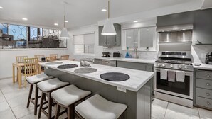 Una cucina moderna con isola centrale, elettrodomestici in acciaio inossidabile e un'area pranzo con sedie in legno.