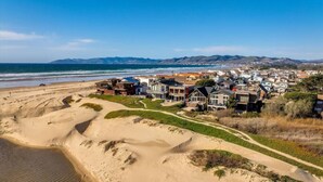 Una zona residenziale costiera con case, una spiaggia sabbiosa e una vista libera sull'oceano.