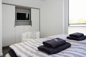 Et moderne hotelværelse med en seng, et fjernsyn monteret på væggen og et vindue med udsigt til det fri.