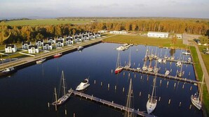 Ein Yachthafen mit mehreren Stegen und Booten, umgeben von einer Wohngegend mit Häusern und einem großen Gebäude.
