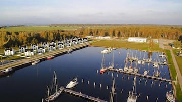 Un puerto deportivo con barcos amarrados, un edificio blanco y una zona verde con árboles.