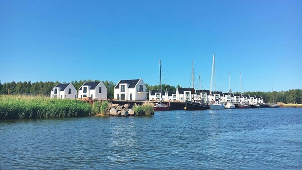 Ein Yachthafen mit mehreren weißen Häusern und Booten, die am Wasser festgemacht sind.