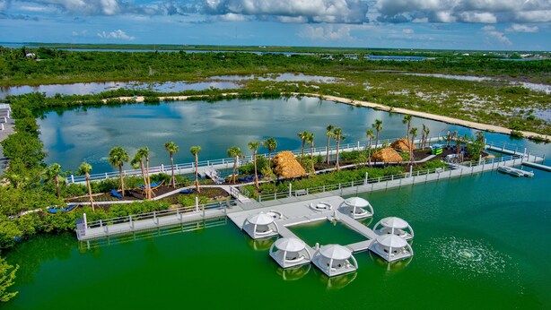 A waterfront hotel with a dock, palm trees, and thatched-roof structures. - Pet-Friendly Lakefront Bunglaow - Sugarloaf Key - Great Amenities (21) (Summerland Key)