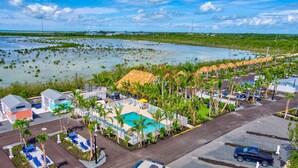 A resort with a pool, palm trees, and a view of a water body.