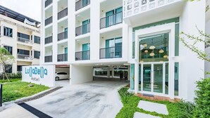 A hotel with a modern design, featuring a multi-story structure with balconies, a covered parking area, and a well-maintained garden. - LullaBella Hotel Patong (Patong)