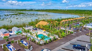Un complexe hôtelier doté d’une piscine, de palmiers et offrant une vue sur une zone de mangroves.
