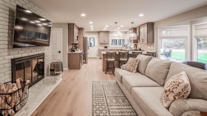 Una cocina moderna con chimenea, zona de comedor y salón con sofá.