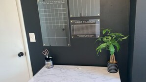 A marble countertop with a plant and a habit tracker on the wall. - NorthEnd Stylish Home Near Hiking Trails & BSU (Boise)