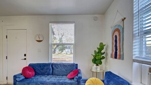 A living room with a blue sofa, a small side table with a plant, and a colorful rug. - NorthEnd Stylish Home Near Hiking Trails & BSU (Boise)