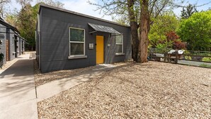 A small, modern building with a dark exterior, a yellow door, and a window. - NorthEnd Charmer 1 bedroom Near BSU (Boise)