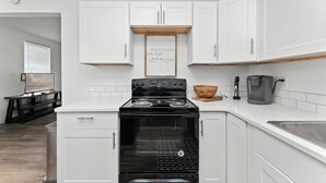 A modern kitchen with white cabinets, a black stove, and a coffee maker. - NorthEnd Charmer 1 bedroom Near BSU (Boise)