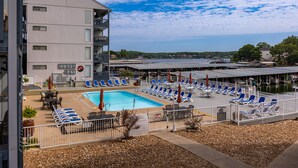 A hotel with a pool area, lounge chairs, and a view of the water. - Lakefront Corner Condo with Boat Slip - Stunning Views - Pool - Laundry (Osage Beach)