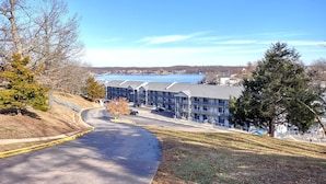 A building with a parking lot and a view of a lake. - Lakefront Corner Condo with Boat Slip - Stunning Views - Pool - Laundry (Osage Beach)