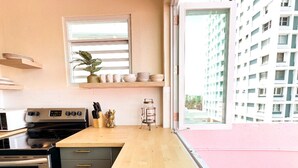 Une cuisine moderne dotée d’un plan de travail en bois, d’appareils électroménagers en acier inoxydable et offrant une vue sur un immeuble de grande hauteur.