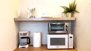 Une cuisine équipée d’une machine à café, d’un four grille-pain et d’un four à micro-ondes, le tout posé sur un plan de travail en bois.
