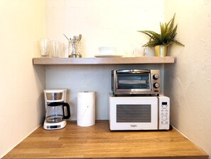 Une cuisine équipée d’une machine à café, d’un four grille-pain et d’un four à micro-ondes, le tout posé sur un plan de travail en bois.