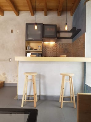 Compact kitchen with stove, microwave, kettle, and toaster, plus a TV above the island.