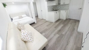 Une chambre compacte et moderne, comprenant un lit, un canapé, une kitchenette et une salle de bain.